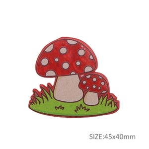 May include: A colourful illustration of two red toadstools with white spots, set on green grass. The larger toadstool is in front of the smaller one. Size: 4.5cm x 4cm.