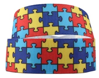 Może przedstawiać: Wstążka w kolorze niebieskim, czerwonym, żółtym i jasnoniebieskim z wzorem puzzli.
