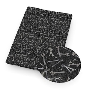 May include: A rectangular piece of fabric featuring a repeating pattern of various silver-colored metal wrenches and small hardware nuts scattered across a dark black background with a textured diamond plate metal pattern throughout the design.