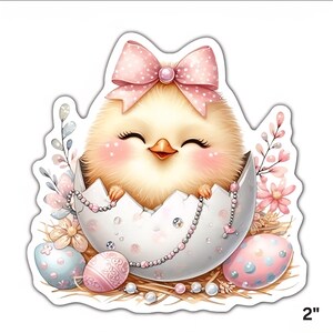 May include: A cute yellow chick with a pink bow and rosy cheeks peeks from a cracked white egg. The egg is decorated with a pearl necklace and surrounded by Easter eggs and flowers. The sticker measures 5 cm.