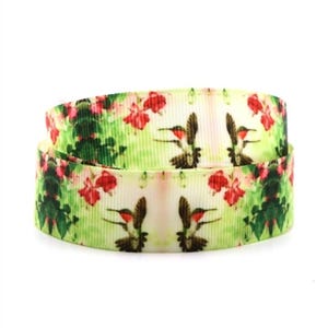 May include: A rolled ribbon featuring a repeating pattern of hummingbirds and flowers. The design includes red flowers, green foliage, and hummingbirds with red throats and green and brown bodies, set against a light green and white background.