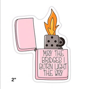 Puede incluir: Una pegatina rosa de un encendedor con el texto "MAY THE BRIDGES I BURN LIGHT THE WAY". El encendedor tiene una llama con tonos naranja y amarillo. La pegatina mide 5,08 cm de altura.