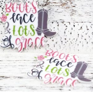 May include: Two white and pink decorative embellishments with the text "Boots, lace & lots of grace" and a gray boot graphic.