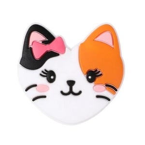 May include: A white, black, and orange cat face with pink ears and a pink bow. The cat has black eyes and a black nose.