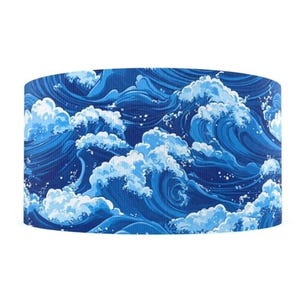 May include: A cylindrical lampshade featuring a repeating pattern of stylized ocean waves in shades of blue and white. The design evokes a sense of movement and the power of the sea. The waves are detailed with white foam and splashes.
