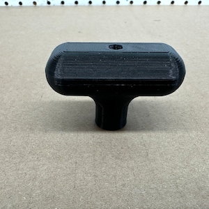 May include: A black plastic T-shaped knob with a hexagonal hole in the top.