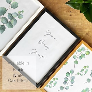 May include: A framed print with the text "You're Doing Great" in black cursive script. The frame is available in black, white, or oak effect.