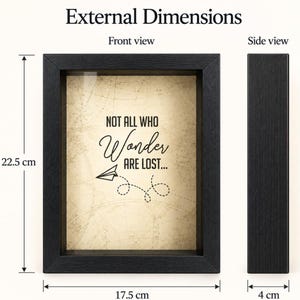 May include: A black shadow box frame with a beige background featuring a map pattern and the text "NOT ALL WHO Wonder ARE LOST..." with a paper airplane graphic. The frame measures 22.5 cm in height, 17.5 cm in width, and 4 cm in depth.