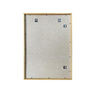 May include: A wooden picture frame with a light brown finish. The frame has a cardboard backing and metal hanging hardware.