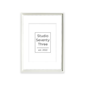 May include: White picture frame with a white mount and a black and white logo that says "Studio Seventy Three est. 2022"