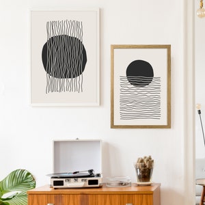 May include: Two black and white abstract line art prints with circles. The print on the left has vertical lines and a circle in the center. The print on the right has horizontal lines and a circle above the lines.