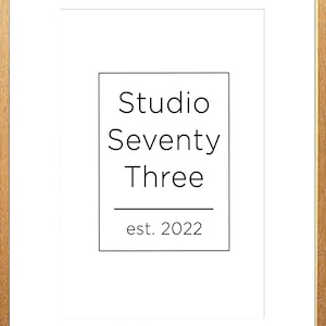 May include: A white framed print with black text that reads "Studio Seventy Three est. 2022".