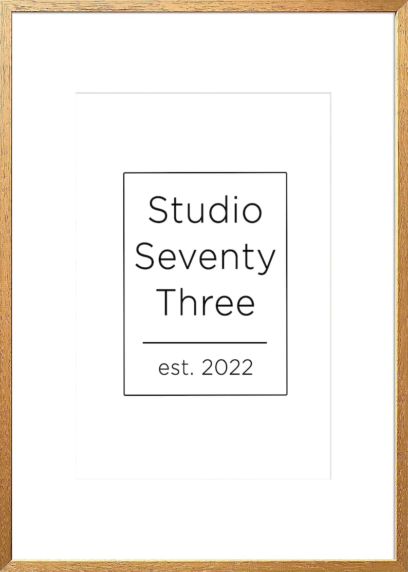 May include: A white framed print with black text that reads "Studio Seventy Three est. 2022".
