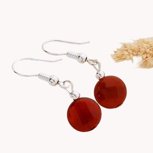 Peut inclure: Une paire de boucles d'oreilles pendantes en argent avec des perles de cornaline rouge.