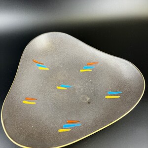 Könnte beinhalten: Eine graue Keramik-Servierplatte mit gelbem Rand und abstrakten blauen, orangen und gelben Designs.