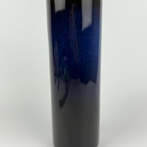 Könnte beinhalten: Eine hohe, zylindrische Vase mit einem dunkelblauen bis schwarzen Verlaufsglasur. Die Vase ist aus Keramik und hat eine glatte, glänzende Oberfläche.