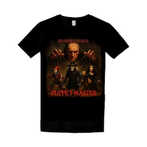 May include: A black short-sleeved t-shirt featuring a graphic print of a puppeteer controlling several figures. The text above reads EVIL COMES IN ALL SIZES and the text below reads PUPPET MASTER in red lettering. The design includes various characters.