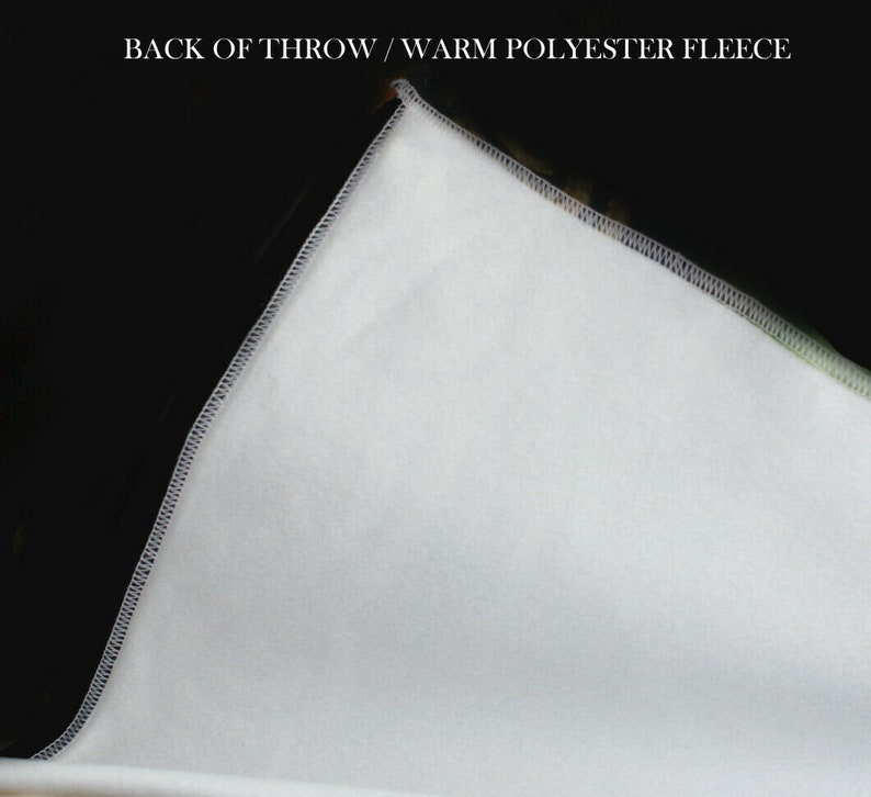 Pu&ograve; includere: Primo piano del retro di una coperta in pile bianca. La coperta ha una texture liscia e morbida ed &egrave; realizzata in pile di poliestere caldo. "Back of Throw / Warm Polyester Fleece" &egrave; scritto in nero nella parte superiore dell'immagine.