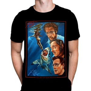 May include: Black t-shirt featuring a movie poster design with a shark attacking a person in the water. The poster includes portraits of three men and the text "THE ART OF RICK MELTON".