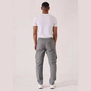 May include: Gray cargo pants with a drawstring waist and multiple pockets. The pants have a zipper fly and a relaxed fit.