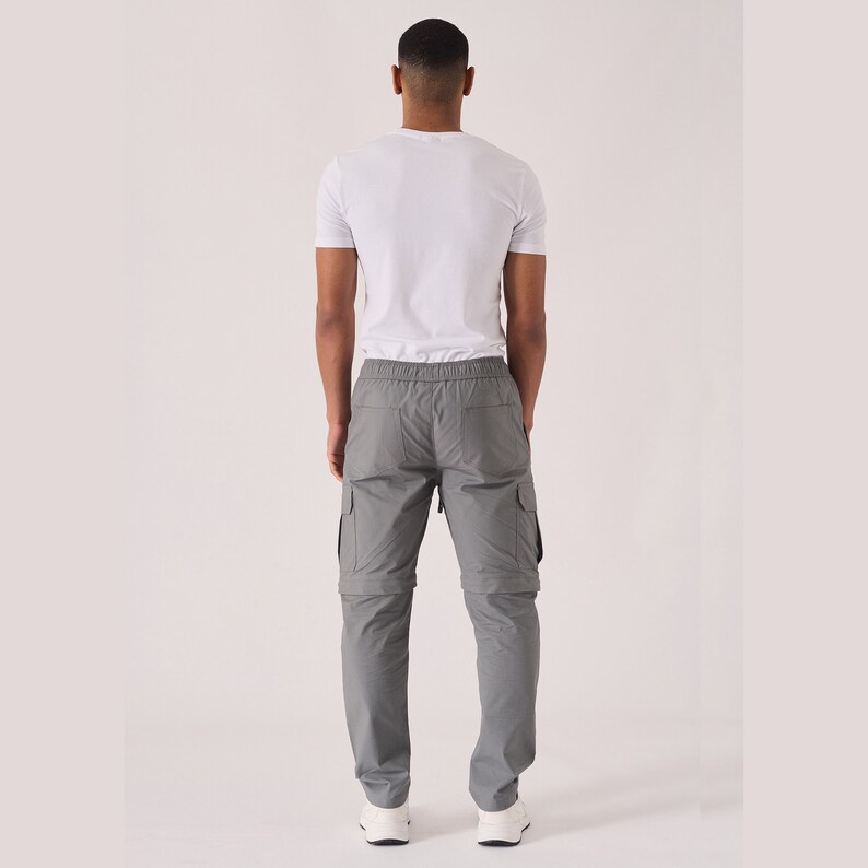 May include: Gray cargo pants with a drawstring waist and multiple pockets. The pants have a zipper fly and a relaxed fit.