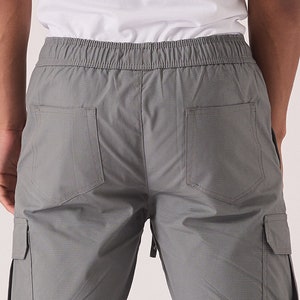 May include: Gray cargo pants with a drawstring waistband and two back pockets.