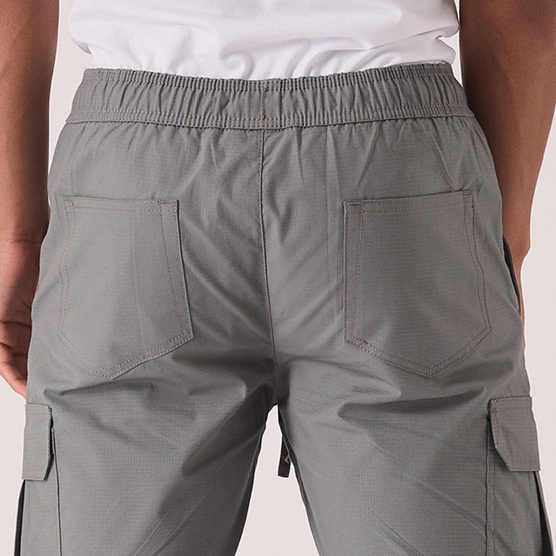 May include: Gray cargo pants with a drawstring waistband and two back pockets.
