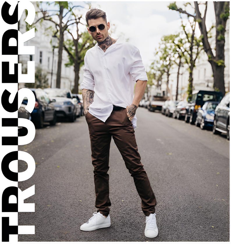 May include: A person wearing a white shirt and brown trousers, with white trainers and sunglasses. The word "TROUSERS" is displayed in large white letters on the left side of the image. The person is standing on a street with parked cars.