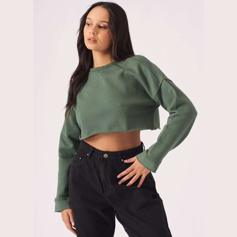 May include: A green cropped sweatshirt with long sleeves and a relaxed fit.