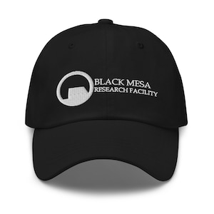 Könnte beinhalten: Schwarze Baseballkappe mit gebogenem Schirm. Die Kappe hat den weißen, gestickten Text "BLACK MESA RESEARCH FACILITY" und ein kreisförmiges Logo auf der Vorderseite. Der Hut ist aus weichem Material.