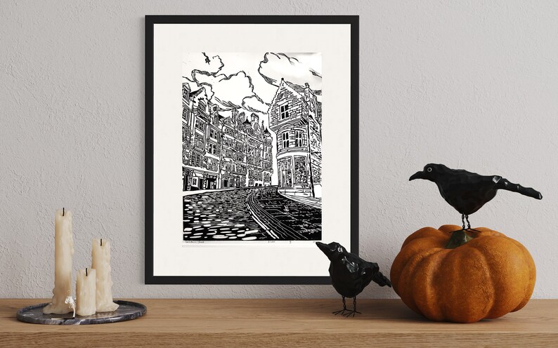 May include: A black and white line drawing of a city street with buildings on either side. The street is cobblestone and there is a building in the background with a sign that says "The Old Curiosity Shop".