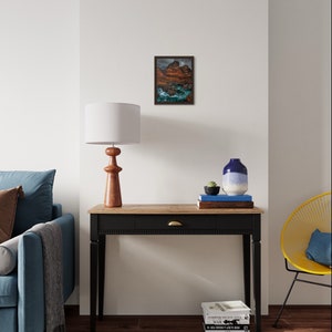 May include: A black console table with a wooden top and a single drawer. The table is decorated with a lamp, a vase, and a stack of books. A blue sofa and a yellow chair are visible in the background.