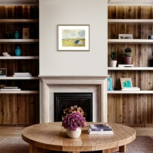 May include: A framed painting of a landscape with a blue sky, white clouds, and a field of yellow flowers. The painting is in a gold frame and is hanging on a white wall.