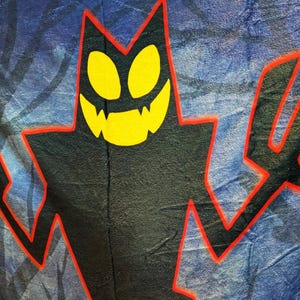Puede incluir: Gráfico negro de una figura diabólica con ojos y dientes amarillos, delineado en rojo. El fondo es un degradado azul y gris con siluetas de árboles, creando un tema de Halloween espeluznante.