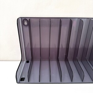 May include: A clear plastic storage organiser with 16 slots for holding items. The organiser is grey and has a hole in the top for hanging.