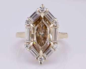 May include: A gold ring featuring a central marquise-cut brown gemstone surrounded by a halo of baguette-cut and round brilliant-cut white diamonds. The setting is crafted in a geometric, elongated hexagonal shape with a polished gold band.