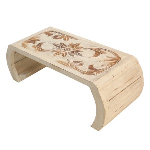 Könnte beinhalten: Weißer Holz-Couchtisch mit einem geschnitzten Blumendesign auf der Oberseite. Der Tisch hat eine geschwungene Basis.