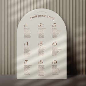 May include: A white arch-shaped seating chart with the text "Find your seat" in brown lettering. The chart is divided into nine sections, each with a number and a list of names.