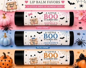 May include: Personalized lip balm favors with a Halloween theme. The image shows three lip balm tubes with black caps, each featuring a ghost holding a sign that says "almost due!" and the text "A Little Boo is Almost Due". The themes are pink, blue, and orange.