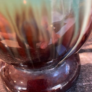 May include: A ceramic vase with a brown and green glaze. The vase has a rounded body and a wide base.