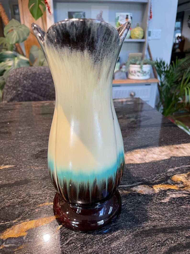 May include: A ceramic vase with a white, blue, and brown glaze. The vase has a wide mouth and a narrow base.