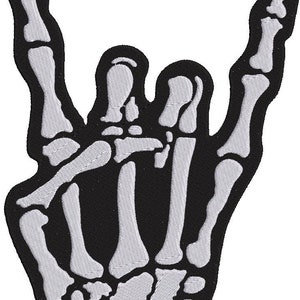 May include: A black and white embroidered patch of a skeleton hand making the rock and roll hand gesture. The patch is perfect for adding a touch of rock and roll to jackets, bags, or other items.