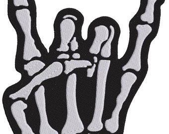 May include: A black and white embroidered patch of a skeleton hand making the rock and roll hand gesture. The patch is ideal for adding a touch of rock and roll to jackets, bags, or other items.