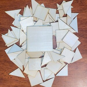 May include: A pile of white wooden squares and triangles. The shapes are arranged in a random pattern.