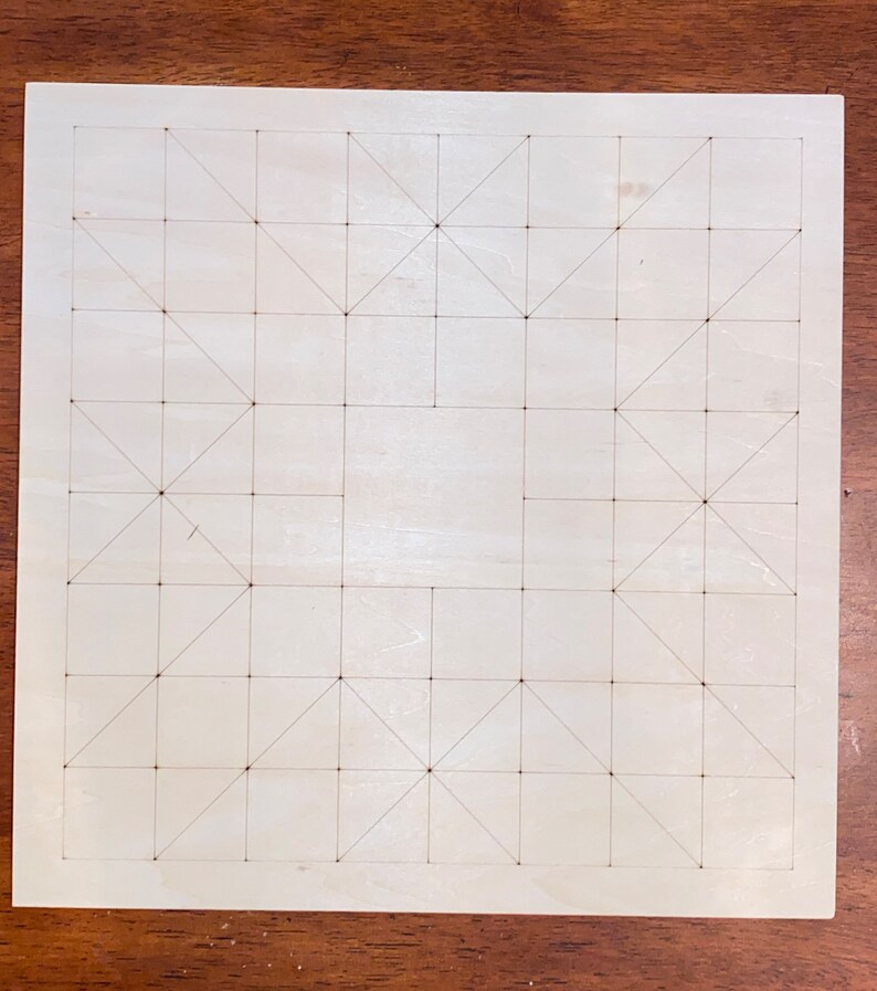 May include: A white wooden board with a grid pattern of squares and triangles drawn on it. The board is used for playing a game.
