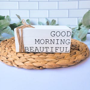 May include: White wooden block with the text "Good Morning Beautiful" stacked on top of each other. The blocks are tied together with twine.