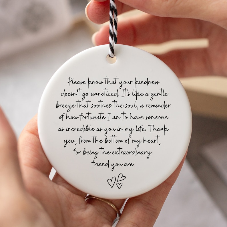 May include: White ceramic ornament with a black handwritten message that reads: "Please know that your kindness doesn't go unnoticed. It's like a gentle breeze that soothes the soul, a reminder of how fortunate I am to have someone as incredible as you in my life. Thank you, from the bottom of my heart, for being the extraordinary friend you are." Two small hearts are drawn at the bottom of the message.