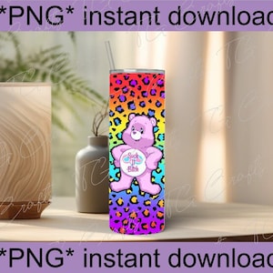 May include: A stainless steel tumbler with a rainbow leopard print design. The tumbler features a pink bear graphic with the text "Suck It Bitch". The tumbler has a straw and is designed for cold beverages.