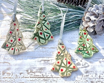 May include: Four handmade ceramic Christmas tree ornaments with a green and white glaze and red polka dots. The ornaments are hanging from silver ribbon.