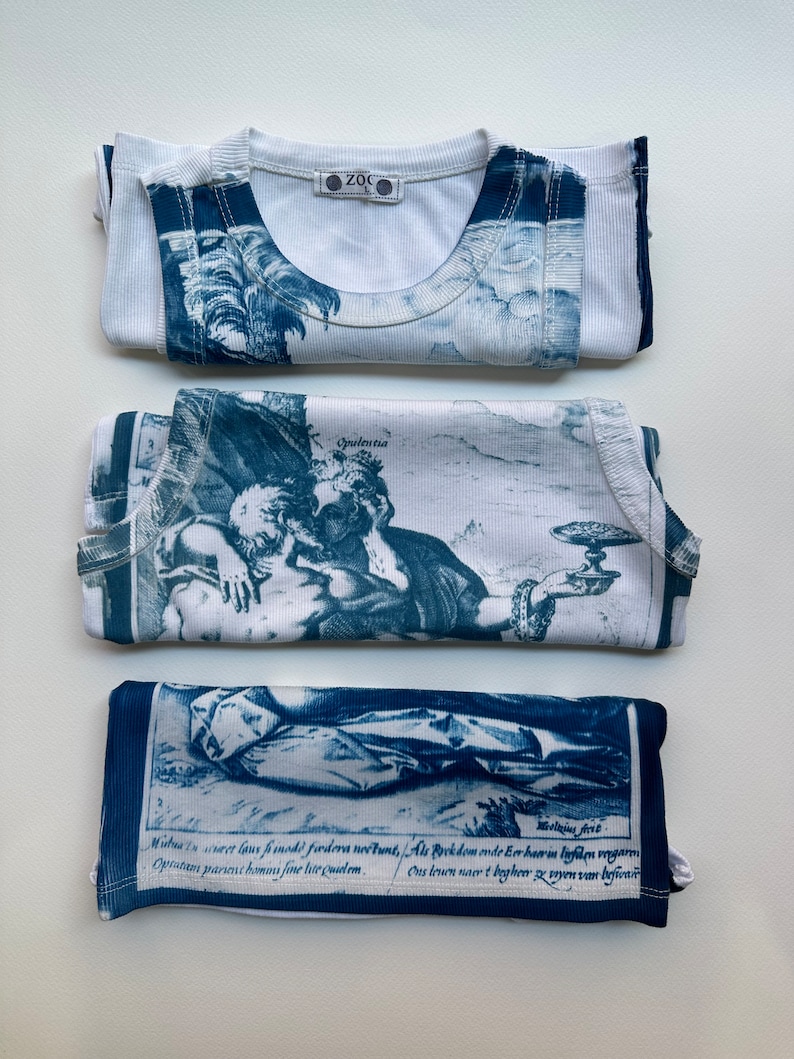 May include: Three white tank tops with blue and white printed designs. The designs are of a landscape, a couple, and a scene with text. The text reads: "Mistus in creet lous frimodi fiodera ne&scaron;tunt, Als Rockdom onde Eer haerin lighten vengarm Opratem parent homms fine lite quidem. Ons leven nacrt bagheer ze soyen van befivar"
